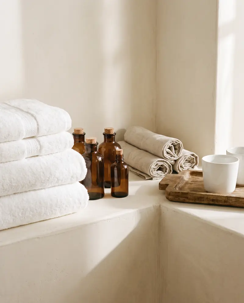 Stacked white towels, amenity bottles and rolled napkins
