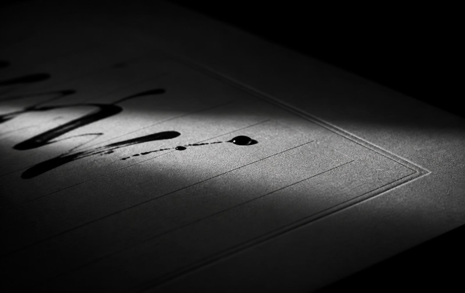 Black ink on a ruled sheet in near darkness